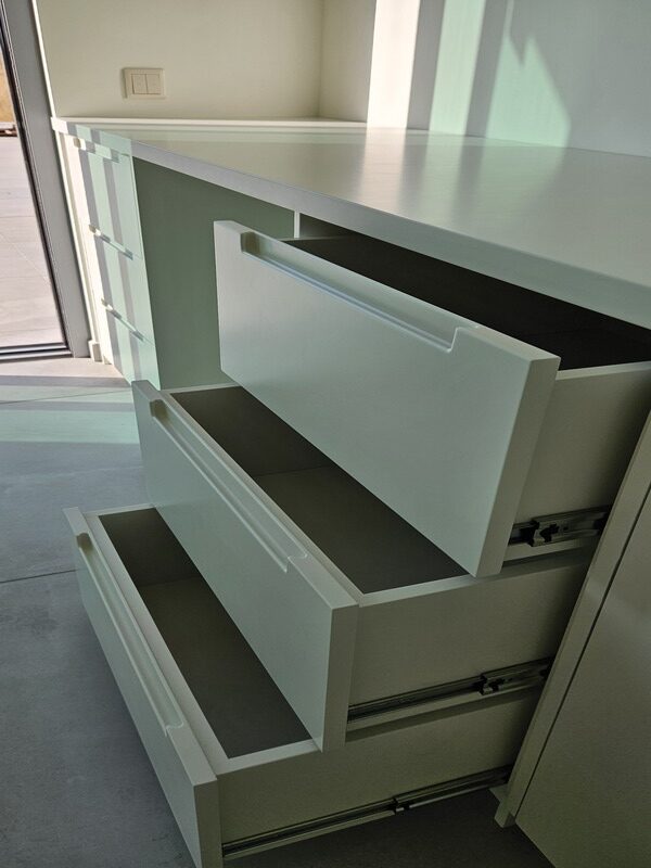 Pormenor de gavetas abertas em móvel de arrumação branco. Marcenaria e carpintaria de interiores com foco em soluções de organização.