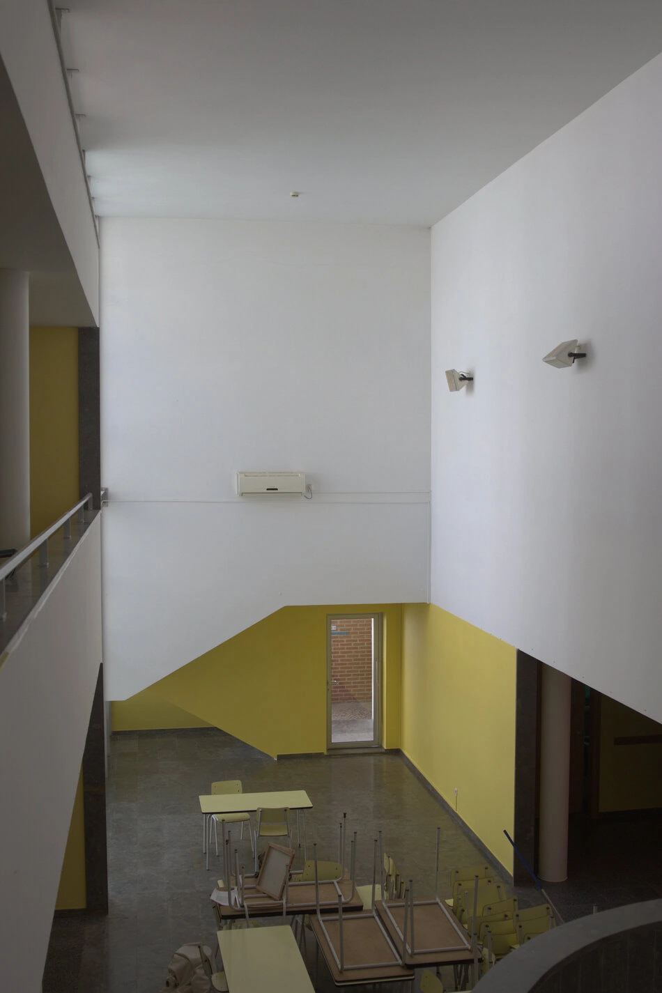 Arquitetura moderna de interior, com paredes brancas e detalhes em amarelo mostarda. Espaço amplo e minimalista.
