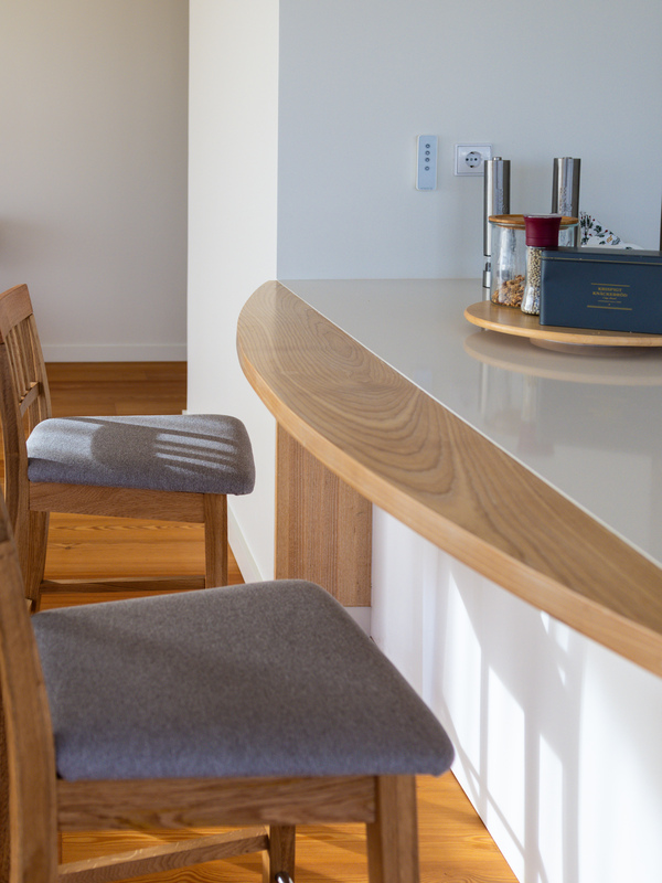 Balcão de cozinha ou bar em madeira curvada, com acabamento superior e cadeiras estofadas. Carpintaria por medida para design de interiores.