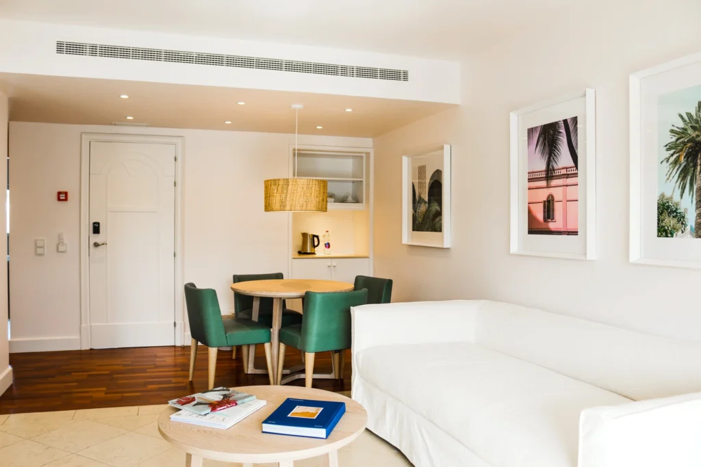 Vista interior do apartamento CAJC mostrando a porta de entrada, sala de estar e zona de refeições moderna e luminosa.