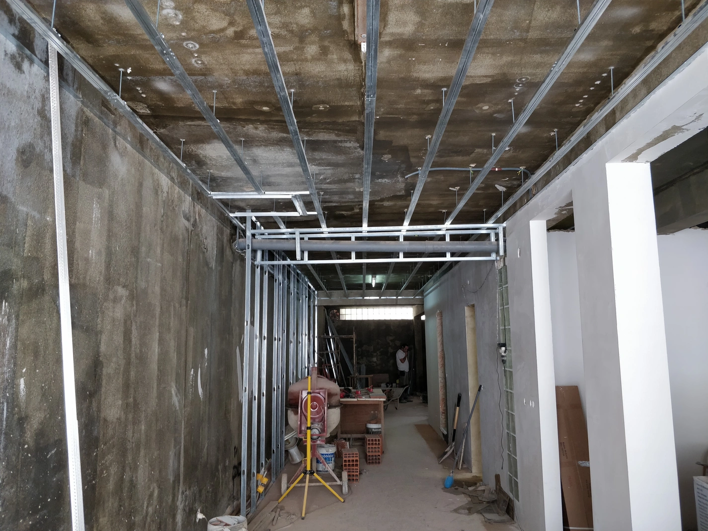 Fase inicial da remodelação: instalação de estrutura metálica para teto falso em perfil de aço galvanizado sob teto de betão. Construção de nova divisória em estrutura de drywall.